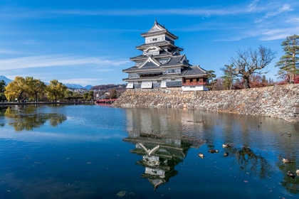 Picture of THE MATSUMOTO CASTLE WITH REFLECTION IN THE MOAT WITH BRIDGE-WALKWAY AND MOUNTAINS BEHIND-JAPAN