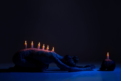 Picture of BURNING CANDLES ON BACK OF LADY BOWING DOWN IN DARKNESS