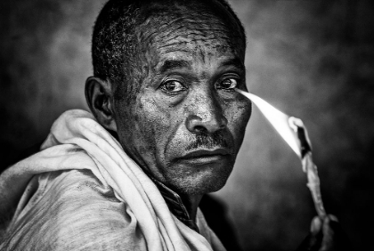 Picture of ETHIOPIAN MAN HOLDING A LIT CANDLE IN A RELIGIOUS CEREMONY.