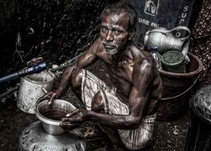 Picture of MAN FILLING A PITCHER WITH WATER IN THE STREETS OF BANGLADESH.