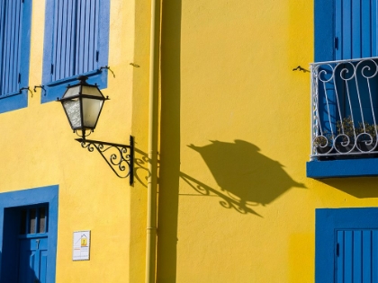 Picture of PORTUGAL-AVEIRO-SHADOW OF STREET LANTERN ON COLORFUL YELLOW BUILDING WITH BRIGHT BLUE SHUTTERS