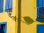 Picture of PORTUGAL-AVEIRO-SHADOW OF STREET LANTERN ON COLORFUL YELLOW BUILDING WITH BRIGHT BLUE SHUTTERS