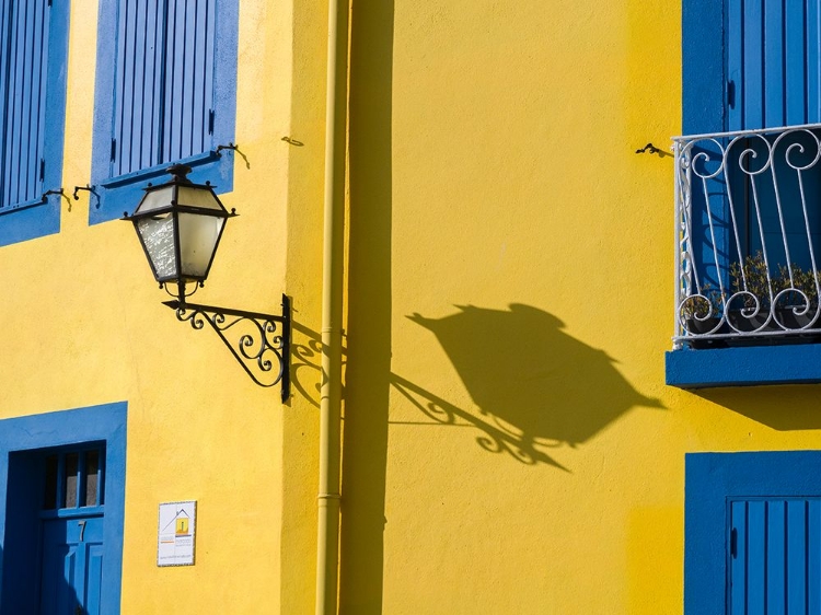 Picture of PORTUGAL-AVEIRO-SHADOW OF STREET LANTERN ON COLORFUL YELLOW BUILDING WITH BRIGHT BLUE SHUTTERS