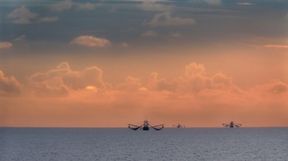 Picture of FISHING BOATS DEEP OUT TO SEA AGAINST THE BACKDROP OF DRAMATIC SUNSET CLOUDS AND SKY