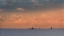 Picture of FISHING BOATS DEEP OUT TO SEA AGAINST THE BACKDROP OF DRAMATIC SUNSET CLOUDS AND SKY