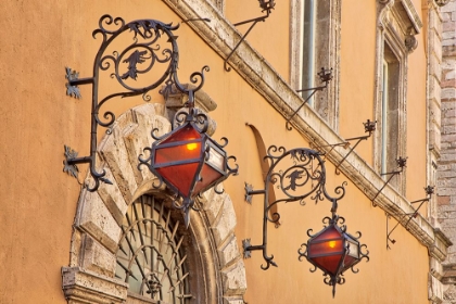 Picture of ITALY- UMBRIA- ASSISI. WROUGHT IRON DRAGON LIGHTS ON A WALL ABOVE AN ENTRANCE.