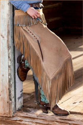 Picture of USA- SHELL- WYOMING. HIDEOUT RANCH COWGIRL STANDING IN DOORWAY WITH COWBOY BOOTS AND CHAPS. 