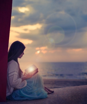 Picture of WOMAN SITTING ON A BEACH WITH ILLUMINATED BOOK