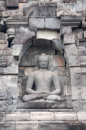 Picture of INDONESIA-JAVA-BOROBUDUR. LARGEST BUDDHIST MONUMENT IN THE WORLD. BUDDHA STATUE IN ORNATE WALL.