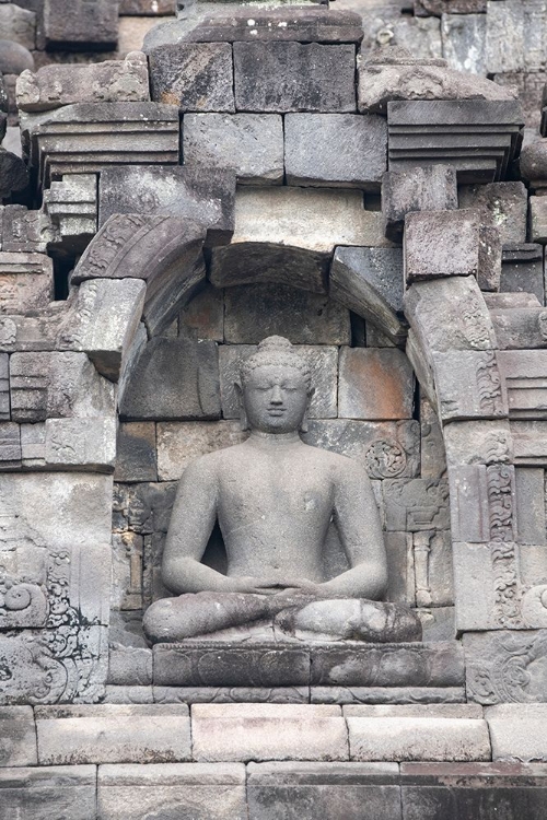 Picture of INDONESIA-JAVA-BOROBUDUR. LARGEST BUDDHIST MONUMENT IN THE WORLD. BUDDHA STATUE IN ORNATE WALL.