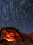 Picture of USA-NEVADA. VALLEY OF FIRE STATE PARK-STAR TRAILS AND CAMPFIRE GLOWING IN SANDSTONE ROCKS