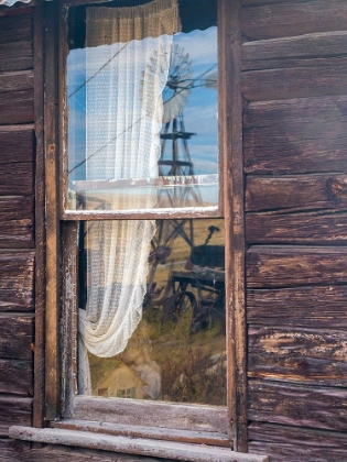 Picture of REFLECTION OF THE WINDMILL AND TRACTOR IN THE WINDOW OF AN OLD BUILDING IN GHOST TOWN.